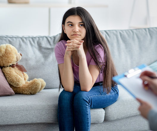 Pensive child sitting on therapist's couch