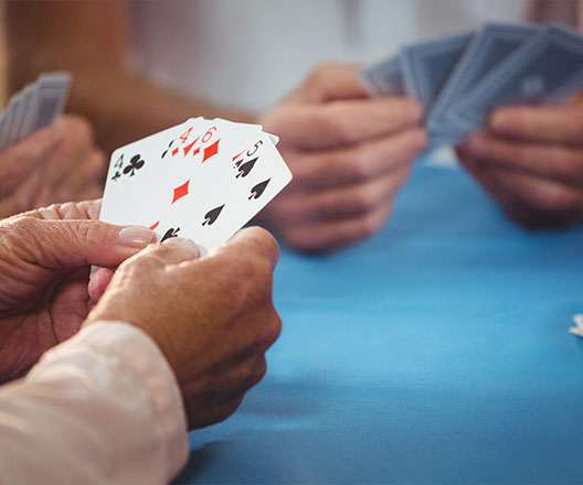 Closeup of players holding their cards at a table.