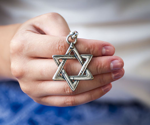 Hands holding star of David necklace.