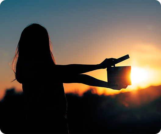 woman holding clapboard against sunset