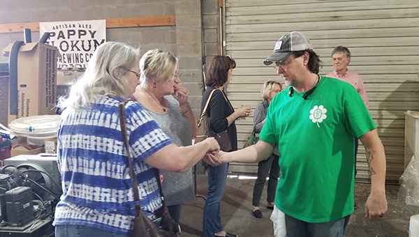 OLLI memebers stand close to one another inside a building with a garage door and accept samples from Jeff Bell.