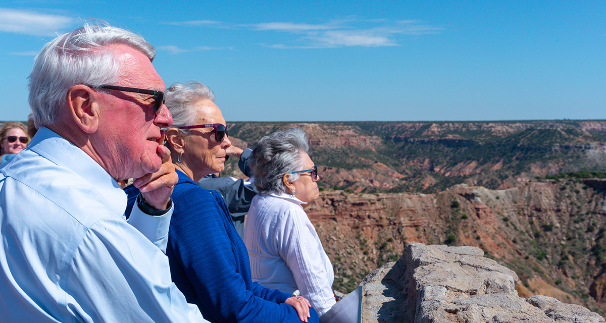 OLLI members at Palo Duro Canyon scenic overlook OLLI members stand atop a canyon while looking to the right over the canyon edge with a clear blue sky
