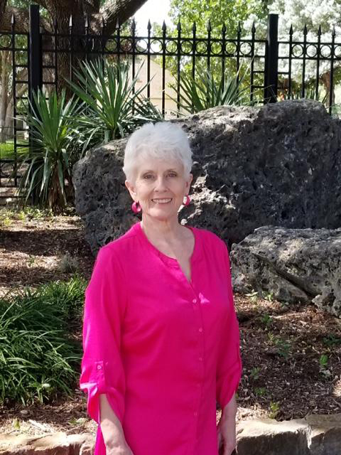 Elaine Waddill A headshot of Elaine Waddill stands outdoors wearing a pink shirt and pink earrings while she smiles at the camera