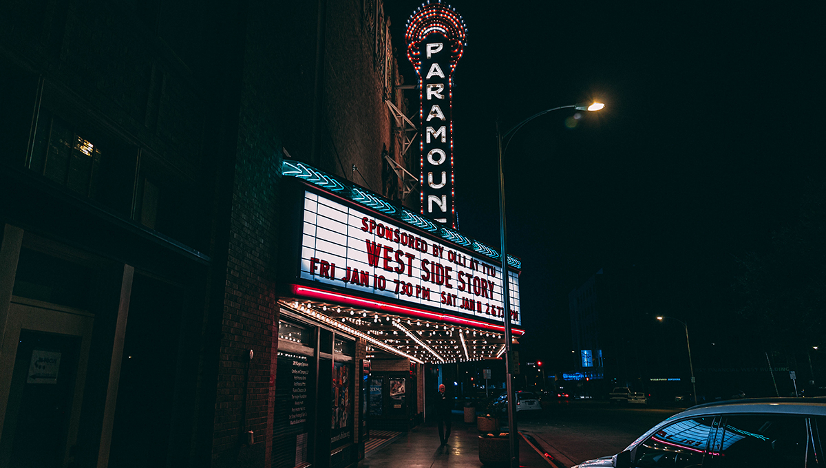 A marquee on the side of a building lit of with colors at night with the words sponsored by olli at ttu westside story 