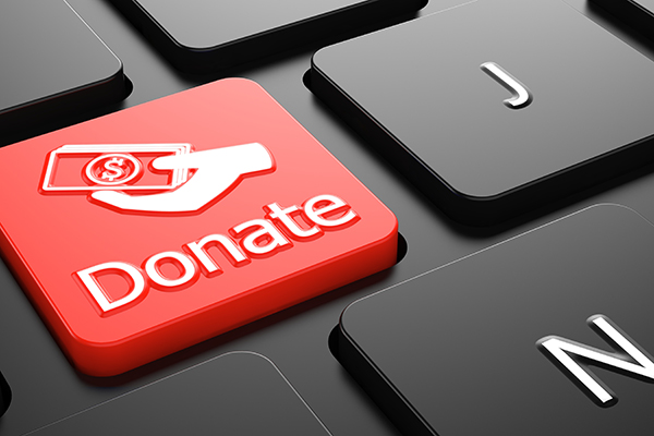 A stock image of a keyboard with black keys and one red key that reads donate with a symbol of a hand with money in it.