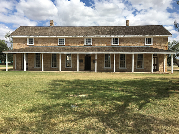 The headquarters building of Fort Concho in San Angelo A frontal view of a two story building with a green grass front lawn.