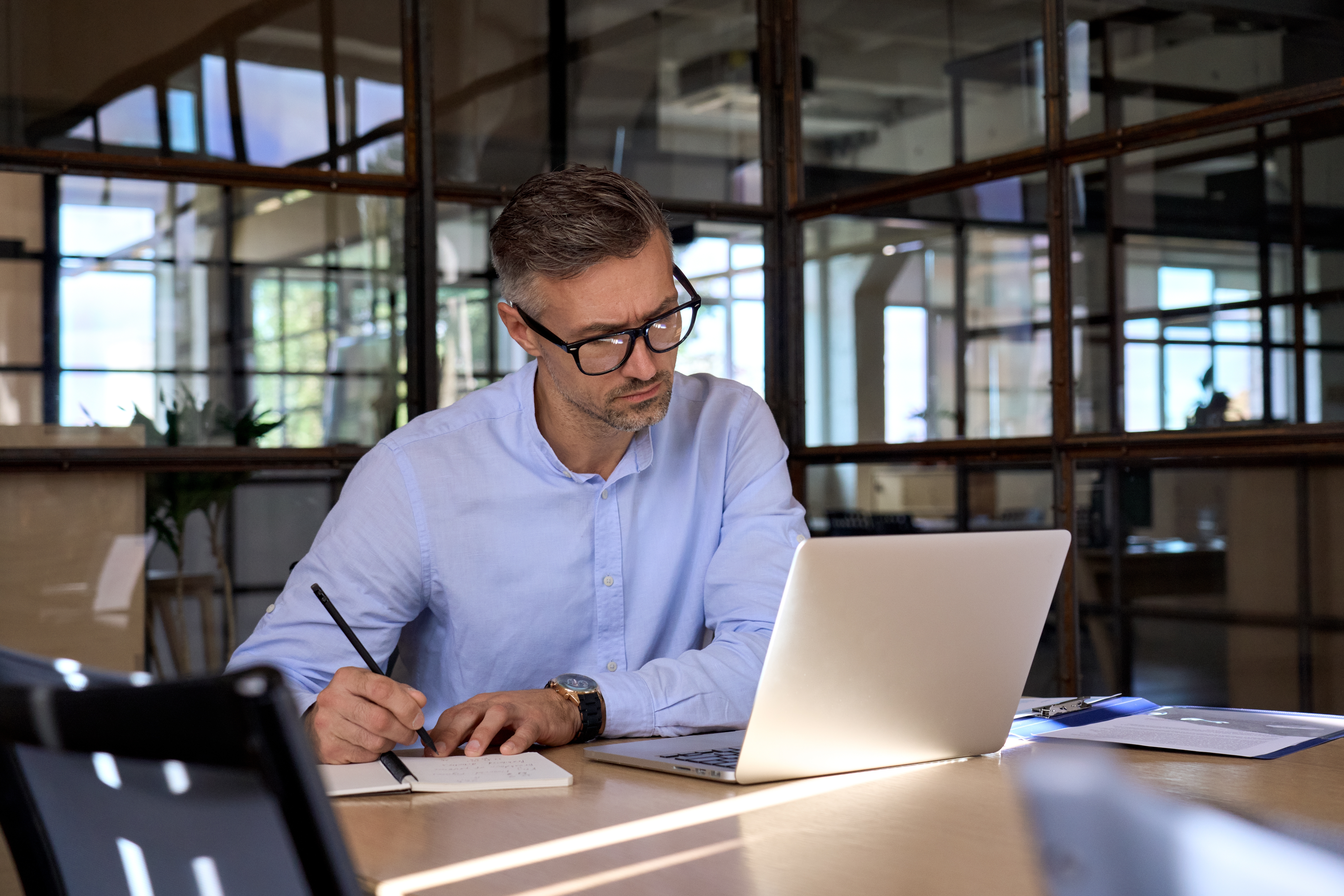 Person taking notes while looking at laptop