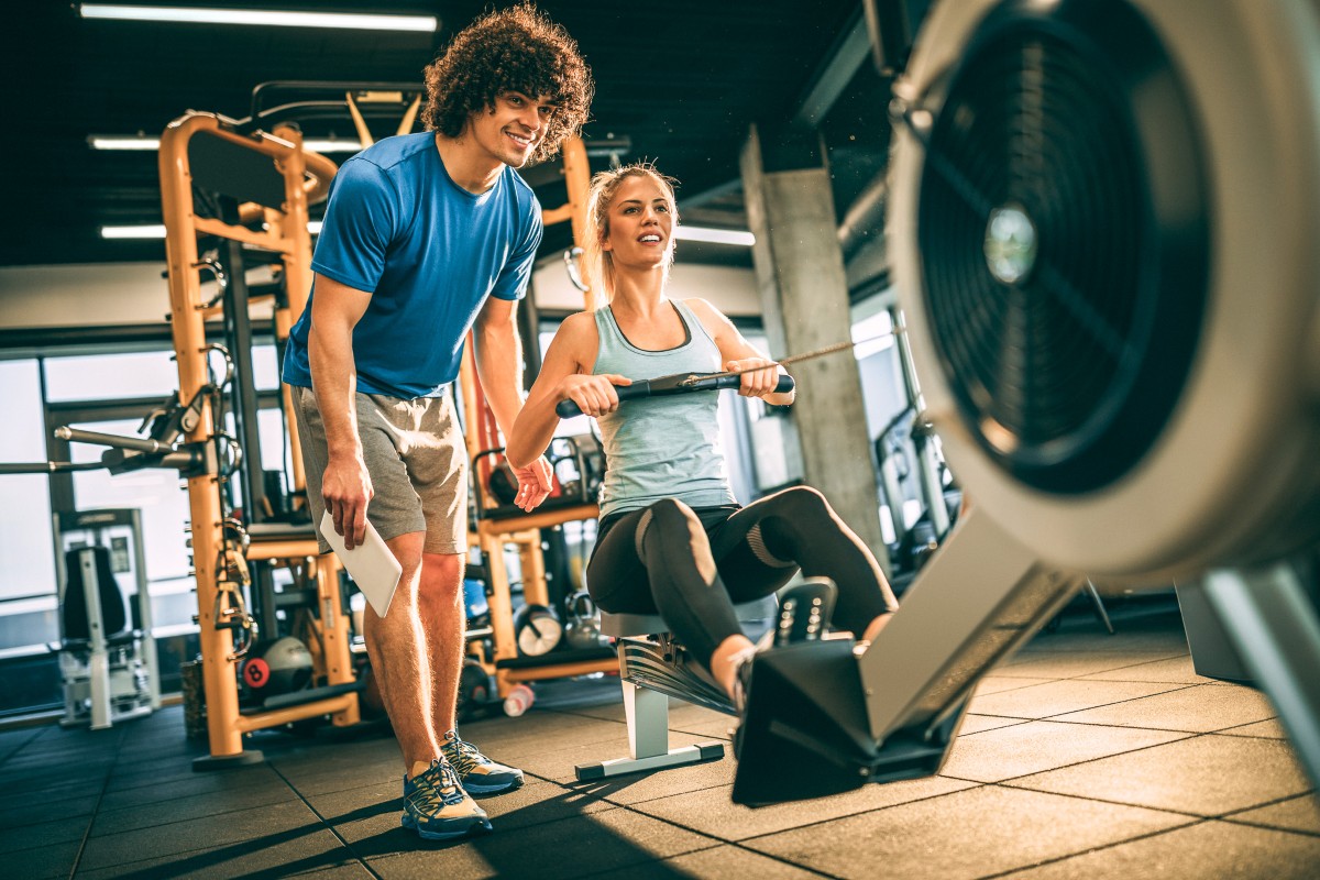 Personal Trainer helping woman on rowing machine