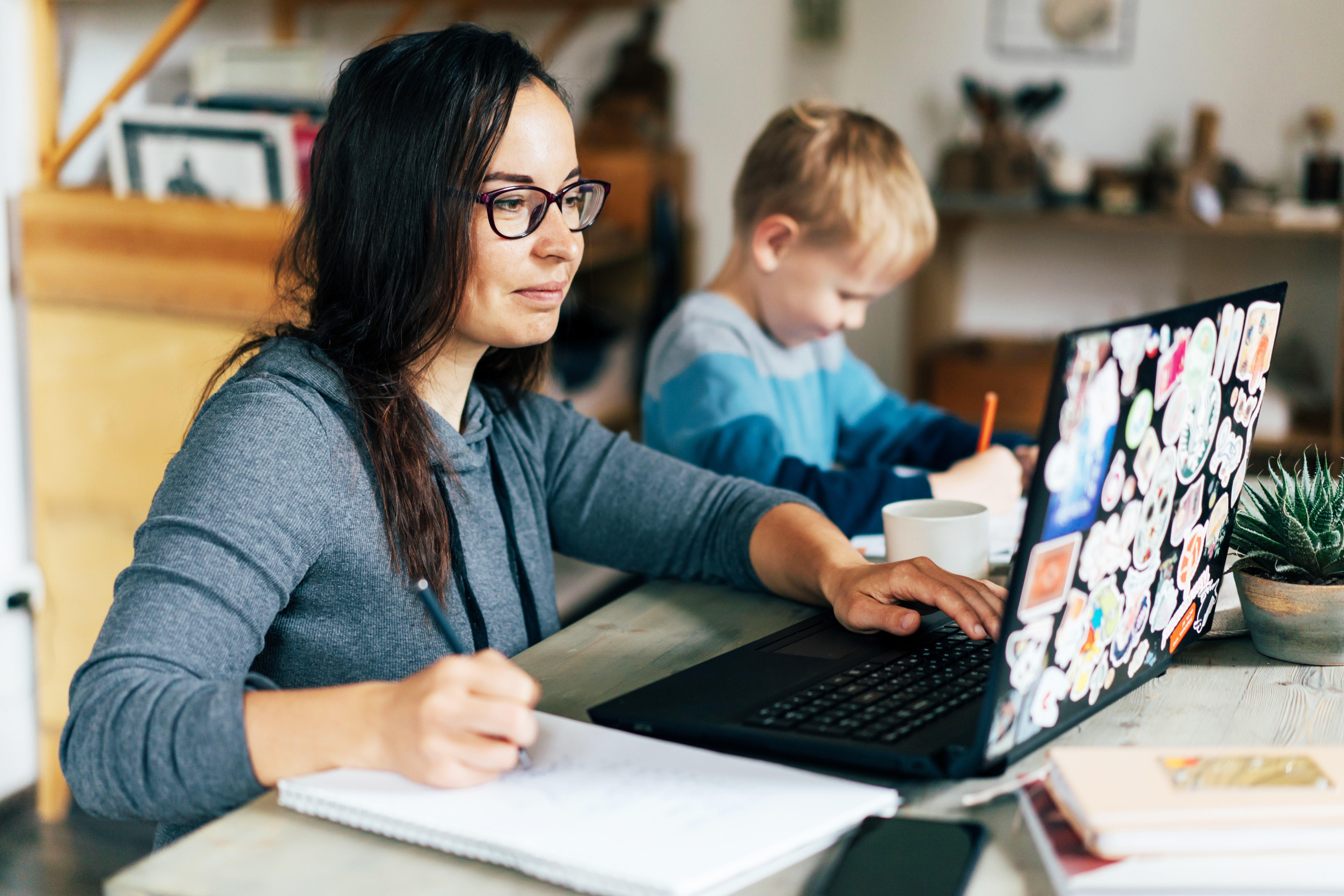 Parent works from laptop with children in background.