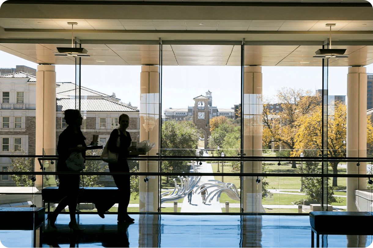 Photo of student silouhettes in front of a glass window inside of a Texas Tech campus building.