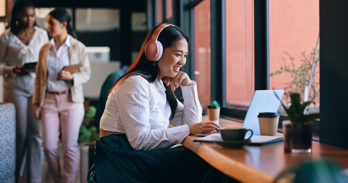 Person with headphones smiles at laptop.