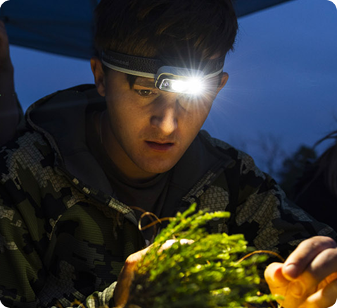 Student looking at a grain at night with a headlamp.