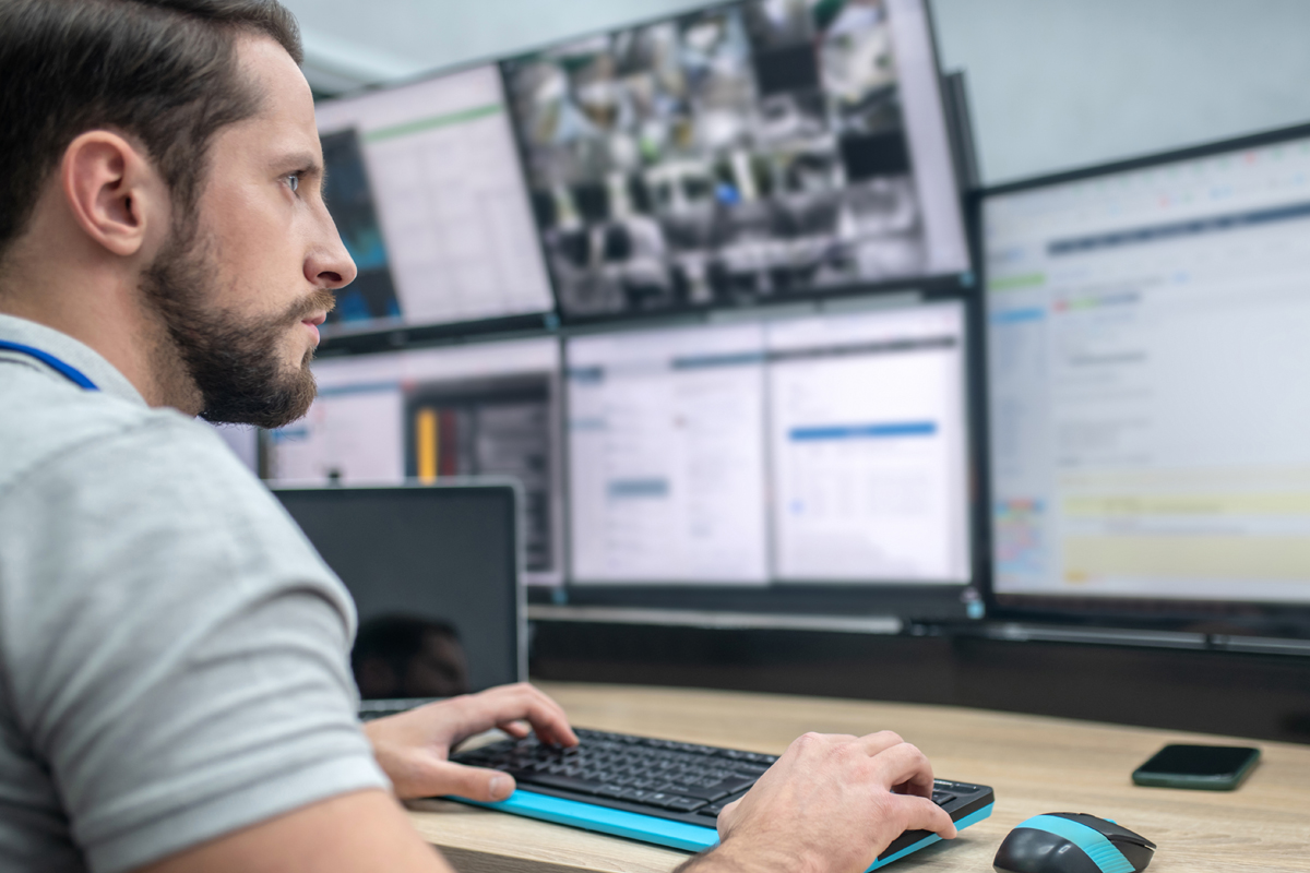 Safety manager sitting in front of multiple computer screens while working.