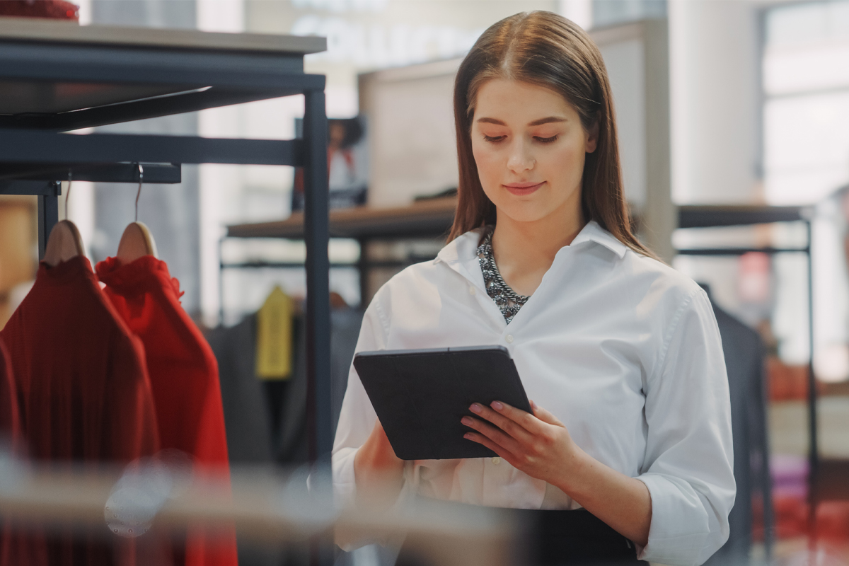 Clothing Store: Female Visual Merchandising Specialist Uses Tablet Computer To Create Stylish Collection.