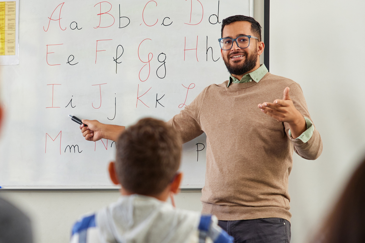 Instructor standing in front of a chalkboard teaching a class.