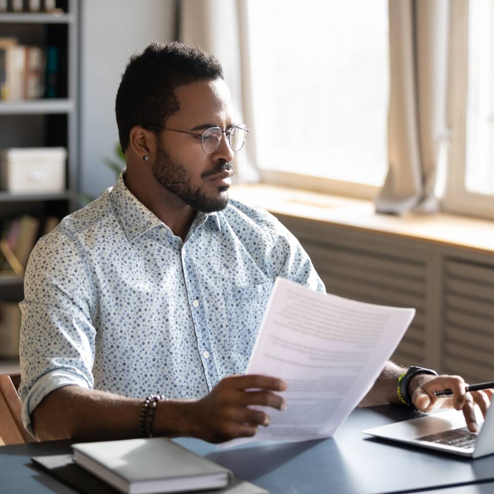 Person with papers working on laptop