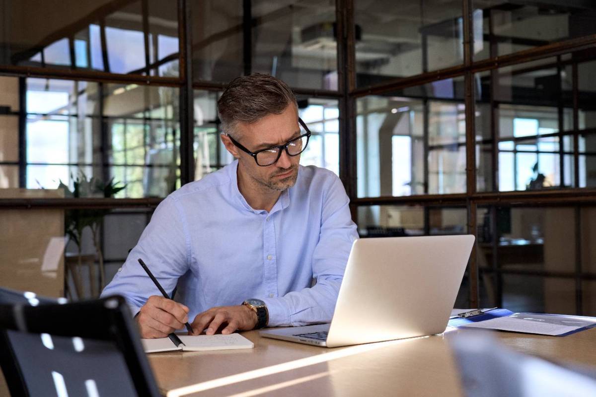 Person taking notes looking at laptop