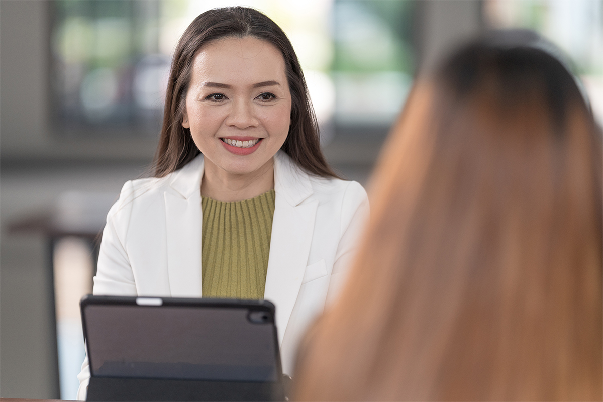 Two people in conversation, one smiling and facing forward while the back of the other person’s head is visible in the foreground.
