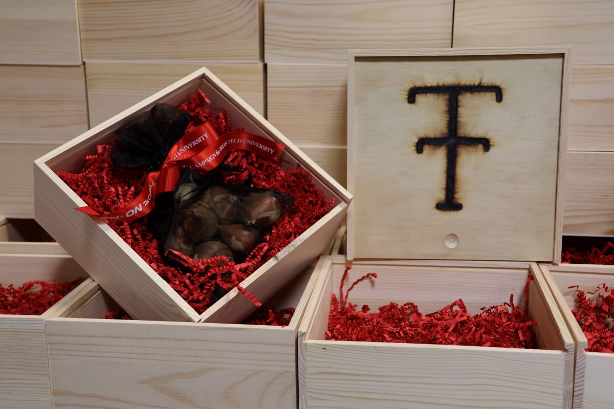 Wooden boxes with the double t branded on the lid with tulip bulbs inside the box wrapped together and tied with a ribbon labeled On & On.