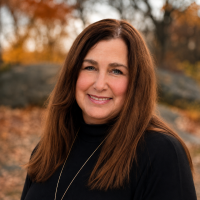 Photo of a woman with long dark hair with a forested background