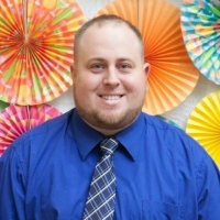Photo of a man in a bright blue shirt and a colorful background