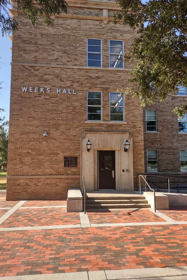 The front of Weeks Hall with a single door accessible by steps and a ramp.