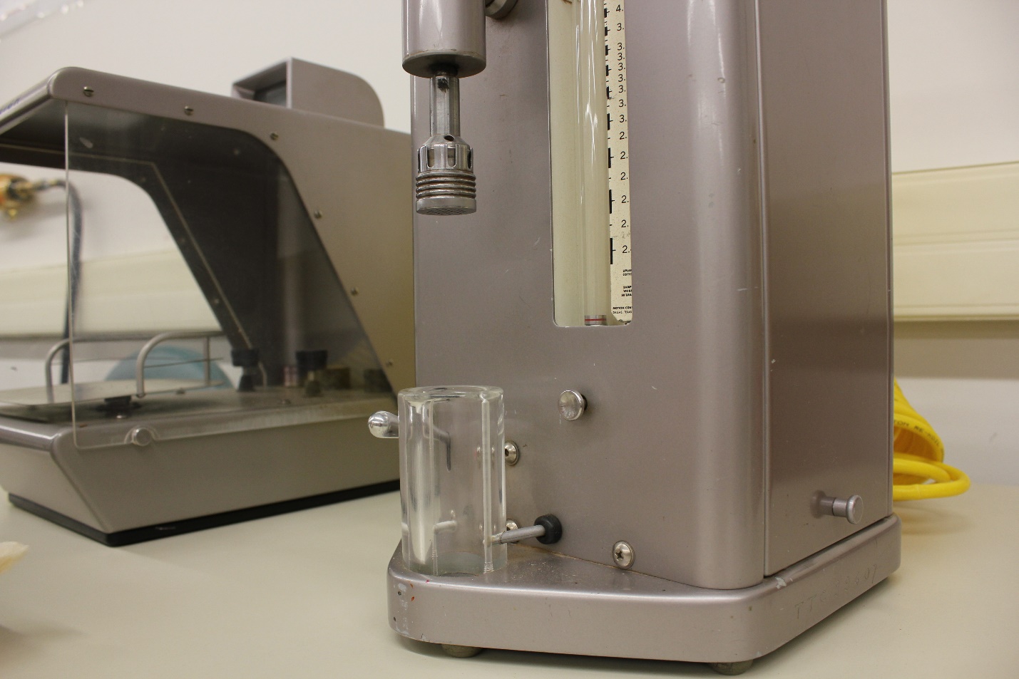 Close-up of Fibronaire plunger and glass sample airflow chamber, Fiberweigh in background.