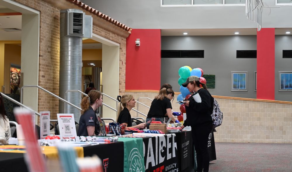 Two college students visiting with a Red to Black peer advocate at a tabling event. 