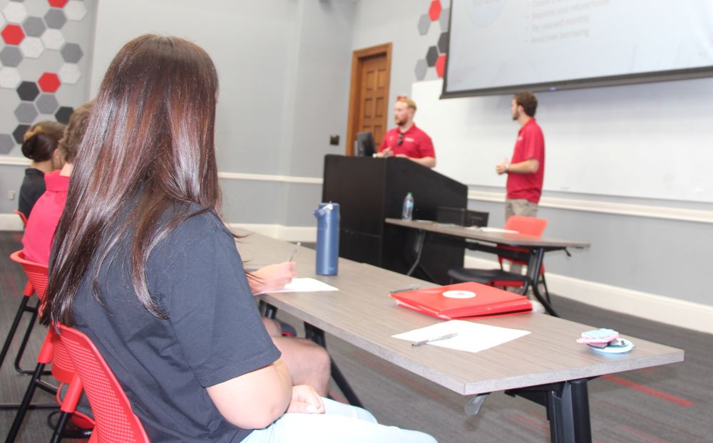 A classroom setting with two speakers giving a presentation to students who are listening attentively.