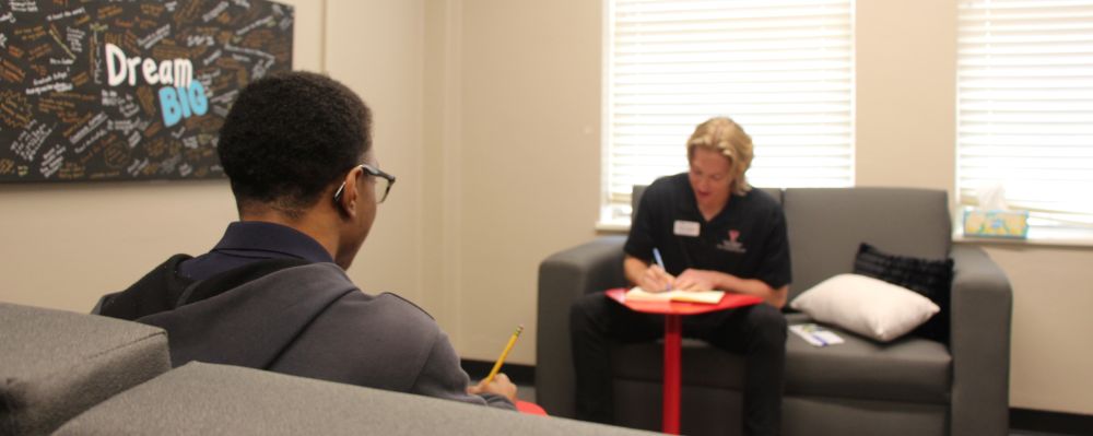 Two students sitting across from each other talking about how to budget.
