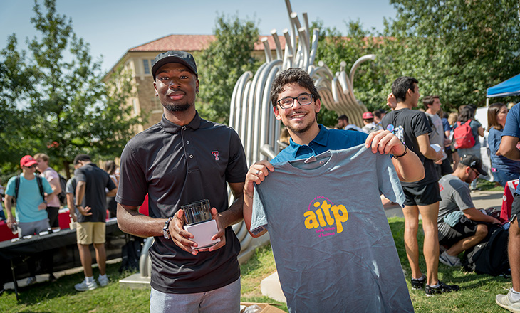 Two students showing shirt of aitp