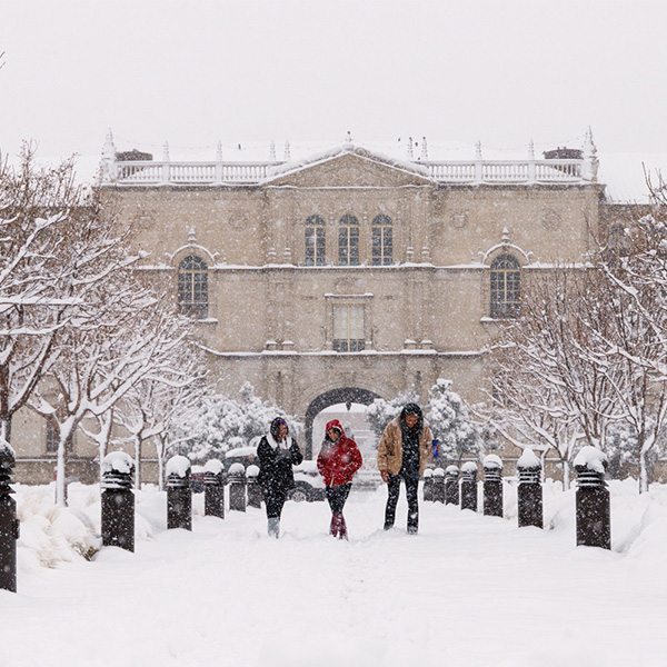 Texas Tech building covered in snow with three students walking along sidewalk