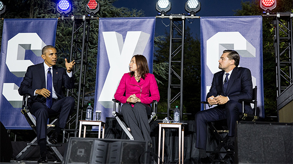 obama, hayhoe and dicaprio on stage talking.