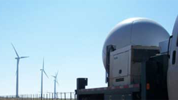 radar on a truck with wind turbines in the background.