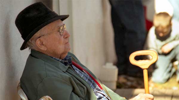 senior citizen leaning against wall with eyes closed