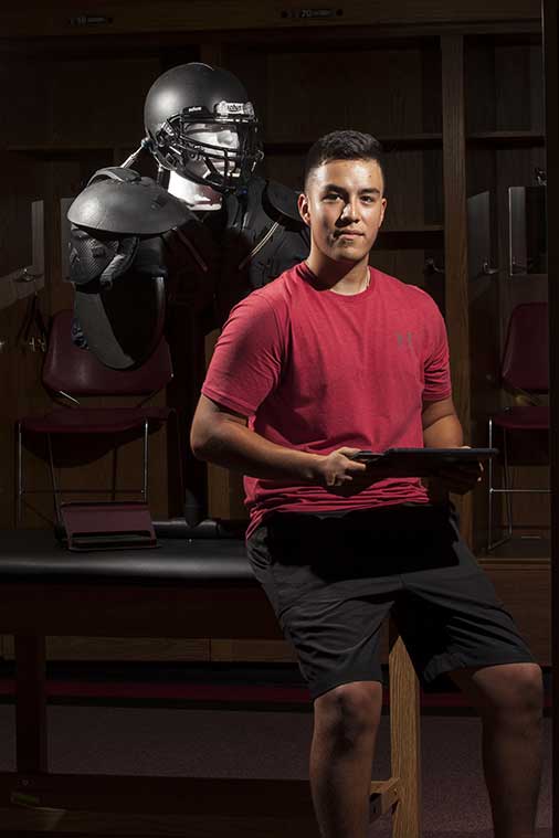 headshot of berto garcia with football helmet prototype in the background