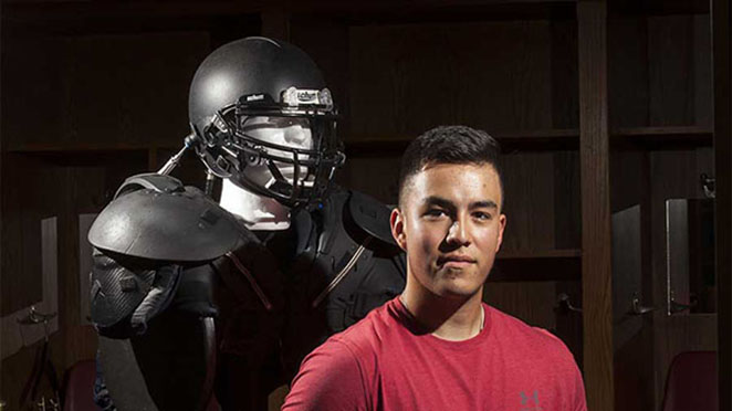 headshot of berto garcia with helmet prototype on mannequin behind him