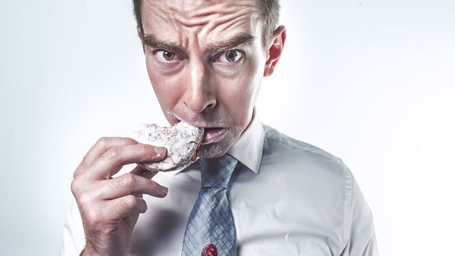 A man with the area of his face surrounding his mouth covered in powder suger and his tie dripping with jelly pictured with an almost accusative expression.