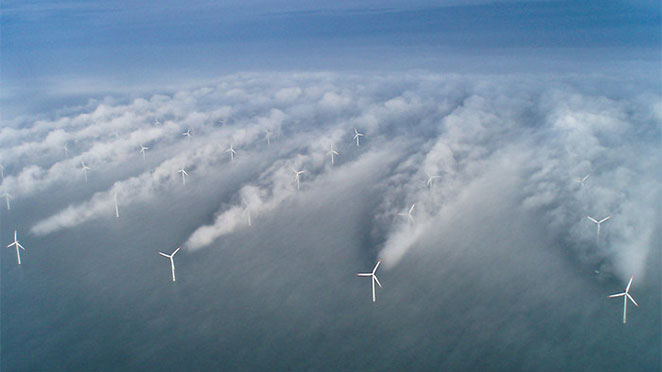 lines of wind turbines with the wake of wind generated behind them visible