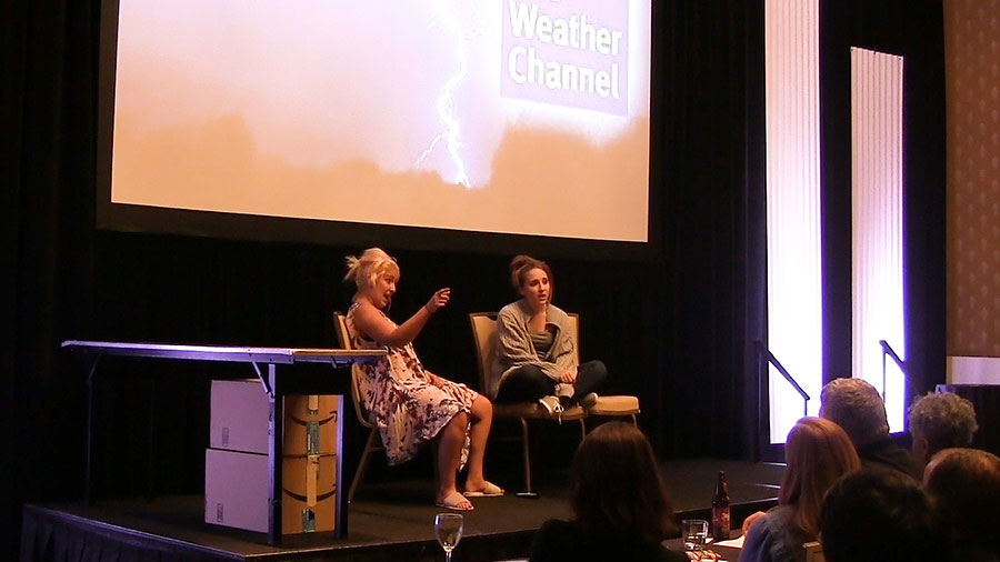 women sitting and talking with weather channel projected behind them