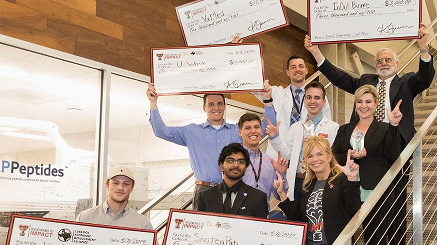 awardees holding up giant checks on stairs