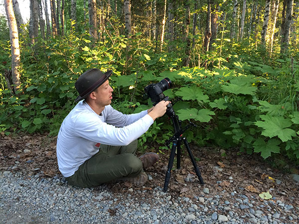 hunton sitting in front of low tripod in woods