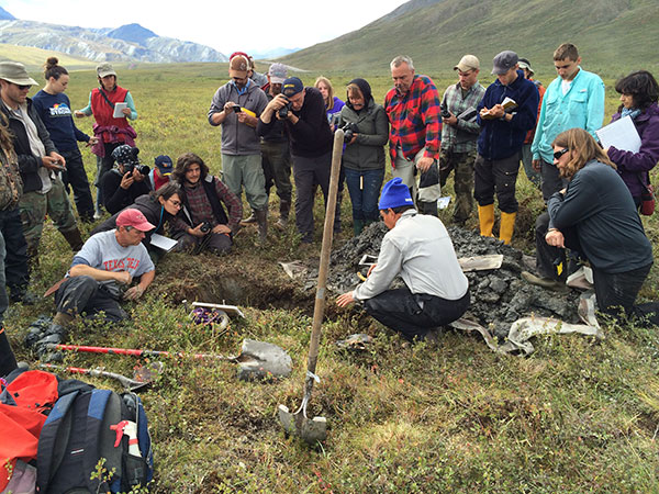 group of students around a large hole