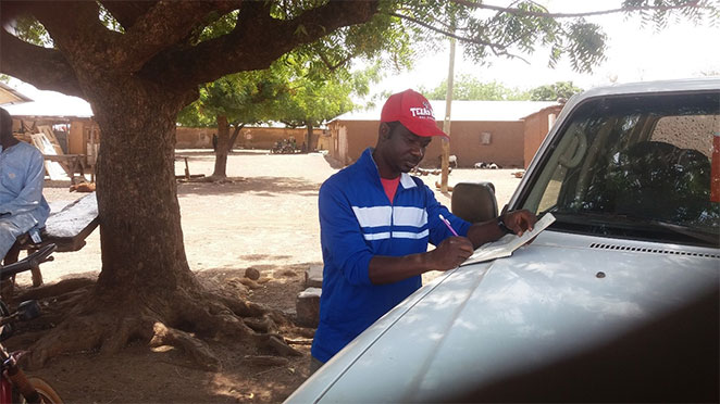 man marking map on hood of his car