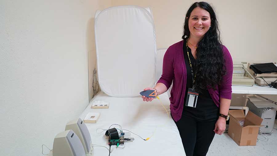 jessica stepp holding a 3d printed object hooked up to an audio device and speakers.