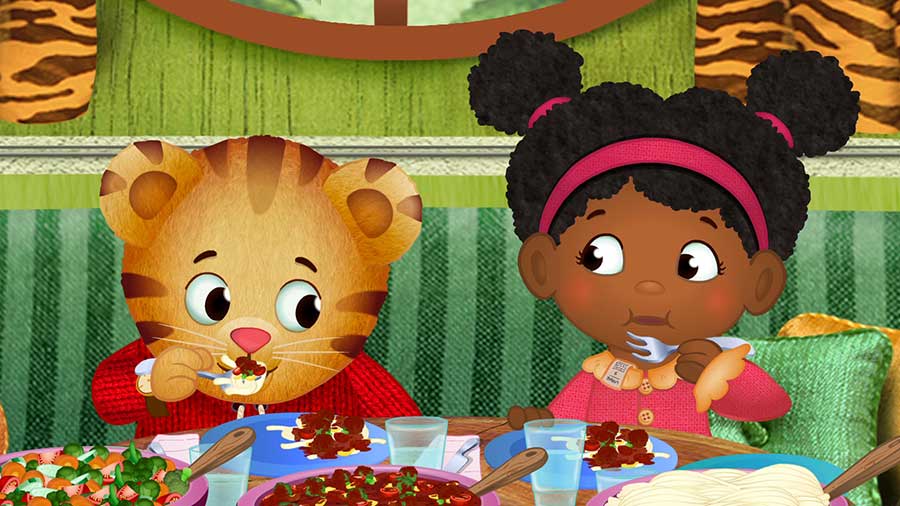 screen cap of show. daniel tiger eating with girl