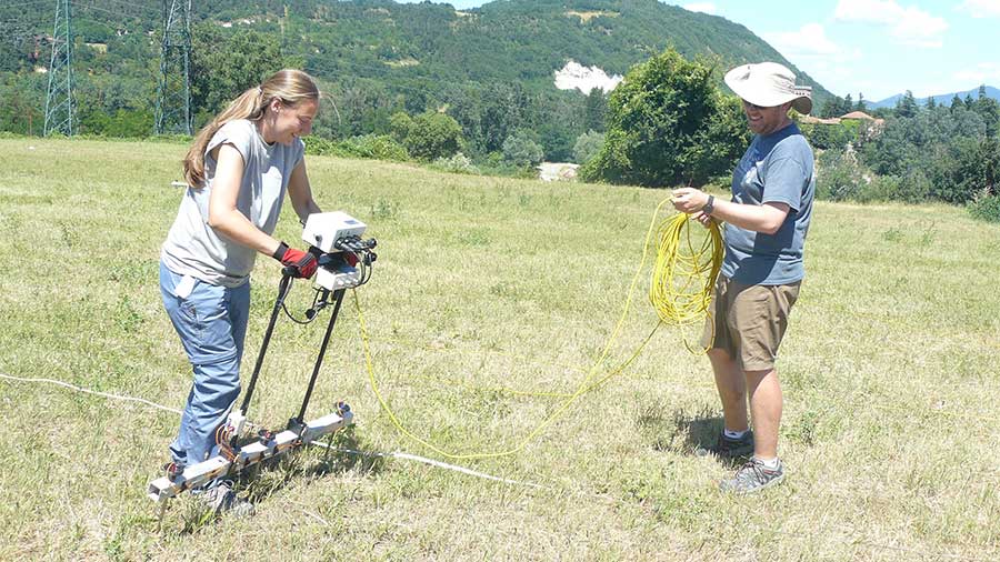 girl operating resistivity machine as boy holds power chord beside her
