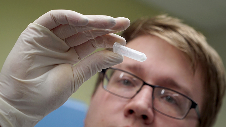 Seifert holding small tube of peptides to light