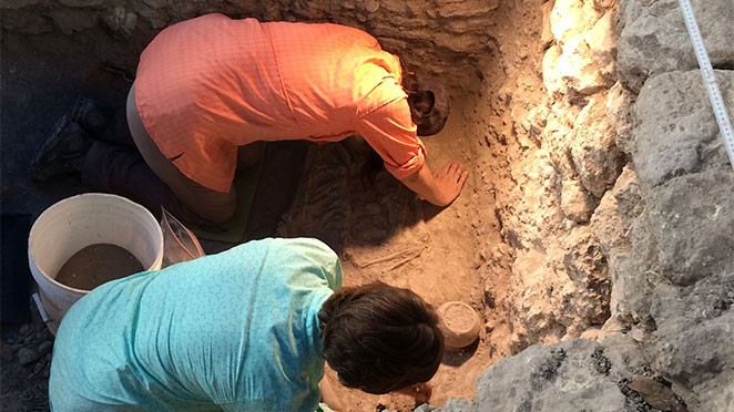 two women in a pit, excavating artifacts