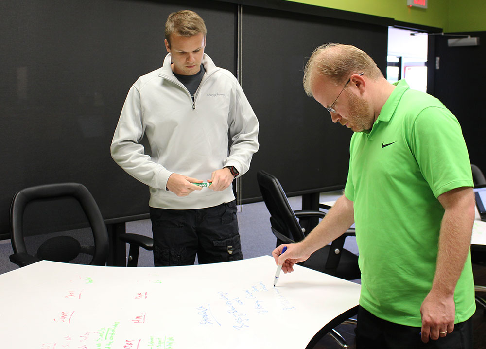 anthony and colleague writing on whiteboard table